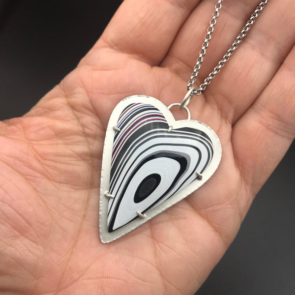 Fordite Heart Shaped Pendant Necklace 7 by tkmetalarts on sterling silver setting, comes on an 18 to 20 inch chain, multicolor off-centered concentric pattern. Shown on hand for scale.