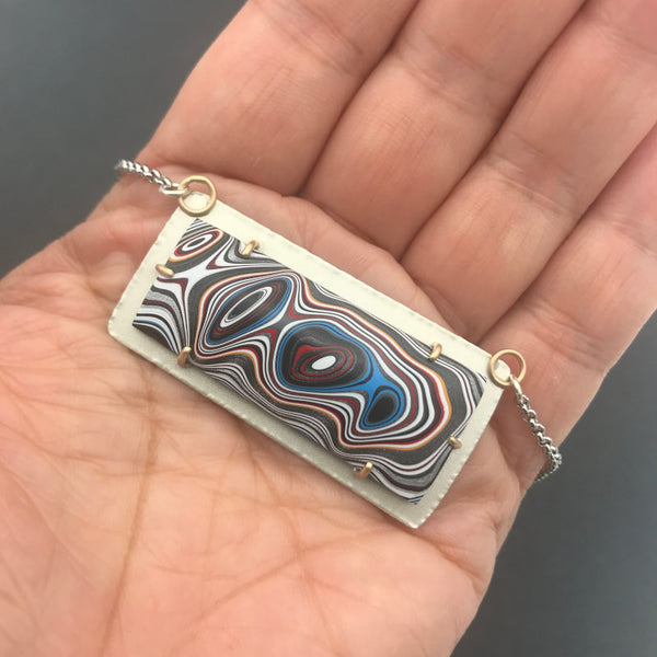 Fordite Pendant Silver and Gold Necklace No 4 by tkmetalarts, sterling silver setting with 18k gold prongs, comes on an 20 to 22 inch chain, multicolor pattern. Shown on hand for scale.